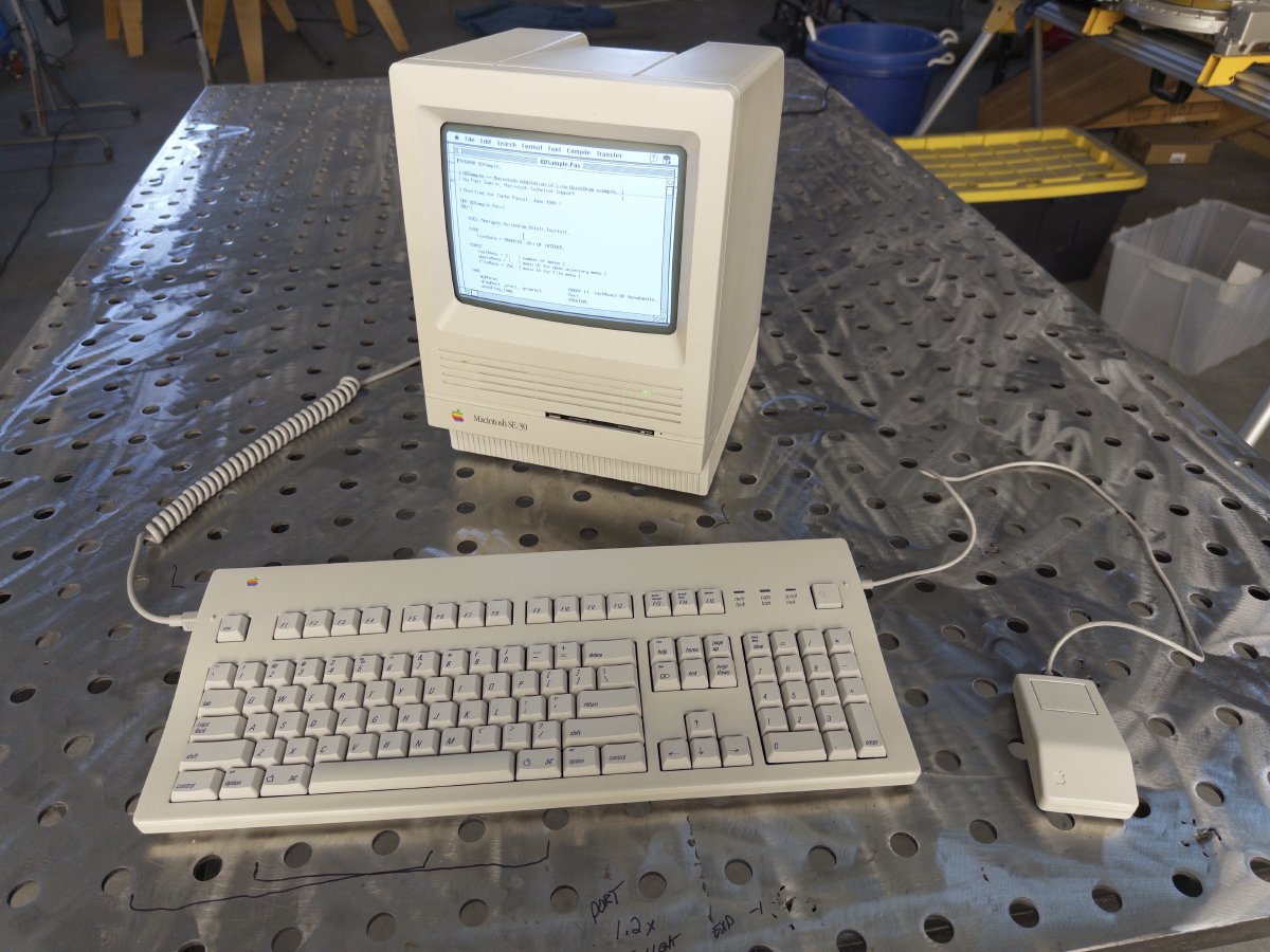 The fully restored Macintosh SE/30 running on a workbench with its original Apple Extended Keyboard II and ADB mouse