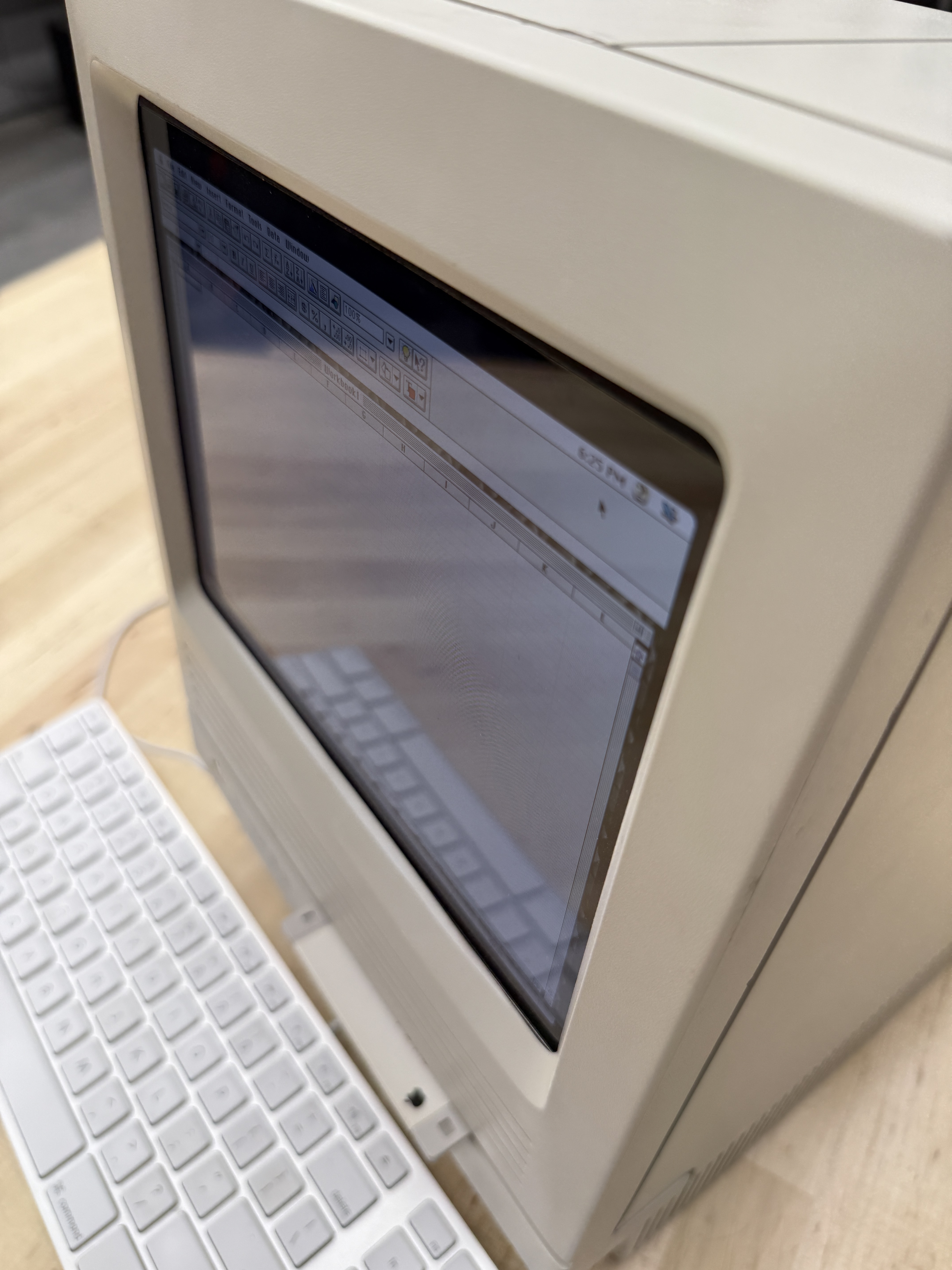 The reimagined SE/30 on a wood desk with a modern white Apple keyboard in the foreground
